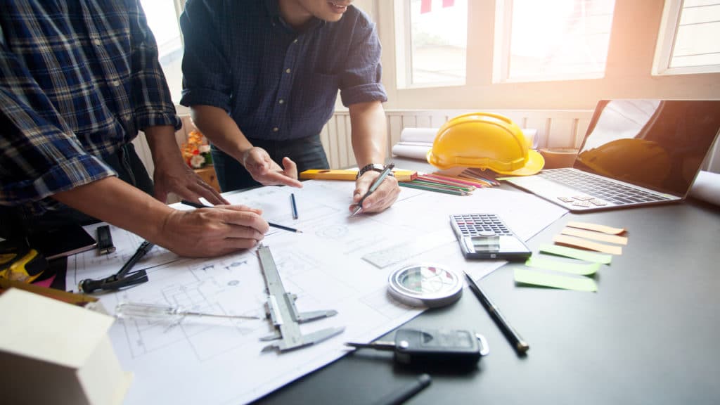 Engenheiro e cliente olhando a planta do projeto.