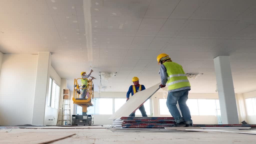 Homens aplicando o drywall em um edifício.